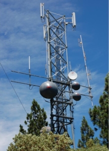 Communications tower with several different antennas standing above treetops
