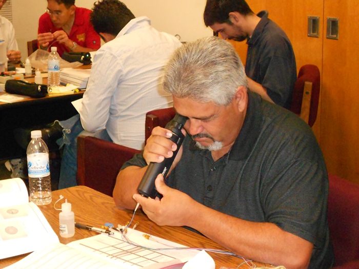 Richard Montoya inspects a connector using an inspection microscope.