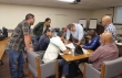 Link, thumbnail, students and instructor gathered around papers on a table
