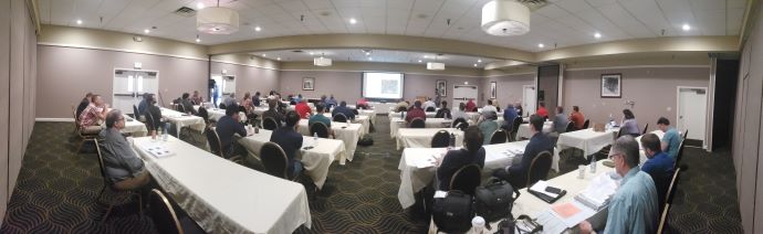 Group of people at tables listening to a speaker in the front of the room