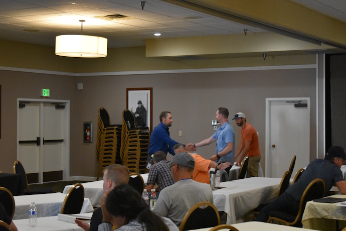 A man shakes hands with another as he hands him a certificate.